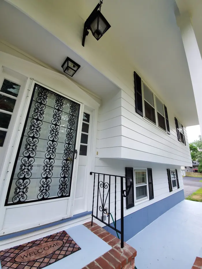 Front entry with fresh white siding, black storm door with scroll insert and painted porch steps